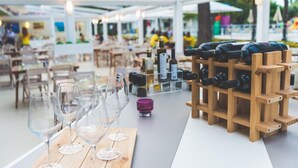 Ein Essbereich im Freien mit Holztischen, Weingläsern und einem Weinkühler.