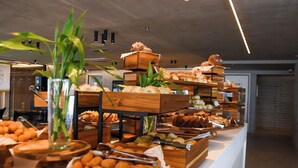 A buffet with various baked goods and pastries displayed on wooden stands and trays. - PORTO ALTO RESORT (Ipojuca)