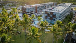 A hotel with multiple buildings, a swimming pool, and palm trees. - PORTO ALTO RESORT (Ipojuca)