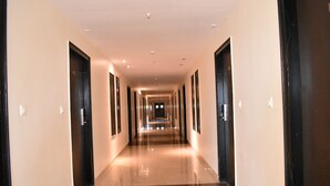 A long, well-lit hallway with doors on both sides, leading to rooms. - Cityhouse - Abora (Kasaya)