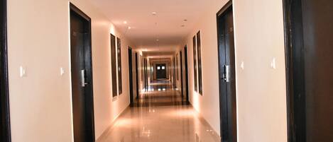 A long, well-lit hallway with doors on both sides, leading to rooms.