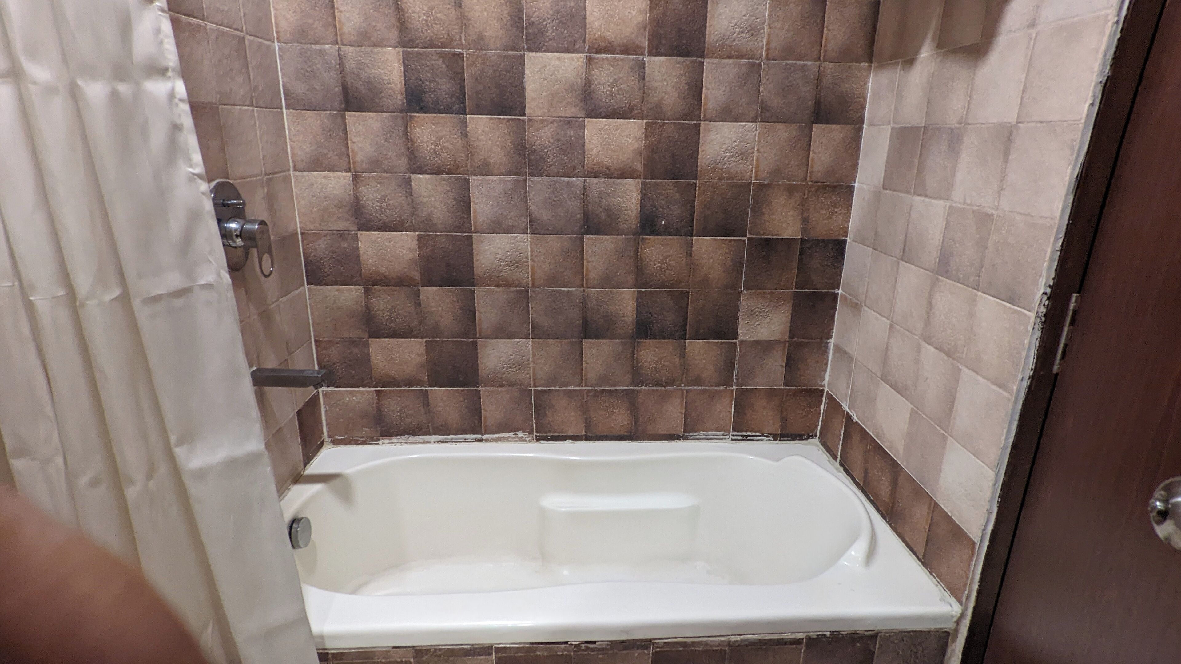 A bathroom with a bathtub, tiled walls, and a door.