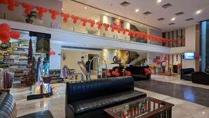 A spacious lobby with a black leather sofa, a glass coffee table, and a reception desk. - Cityhouse - Abora (Kasaya)