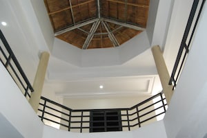 Interior con techos altos, techo de madera y barandilla de metal negro.