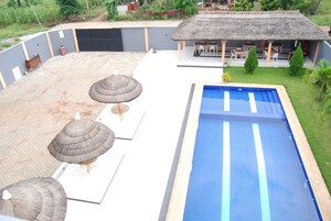 Una piscina con una estructura de techo de paja y sillas de descanso.