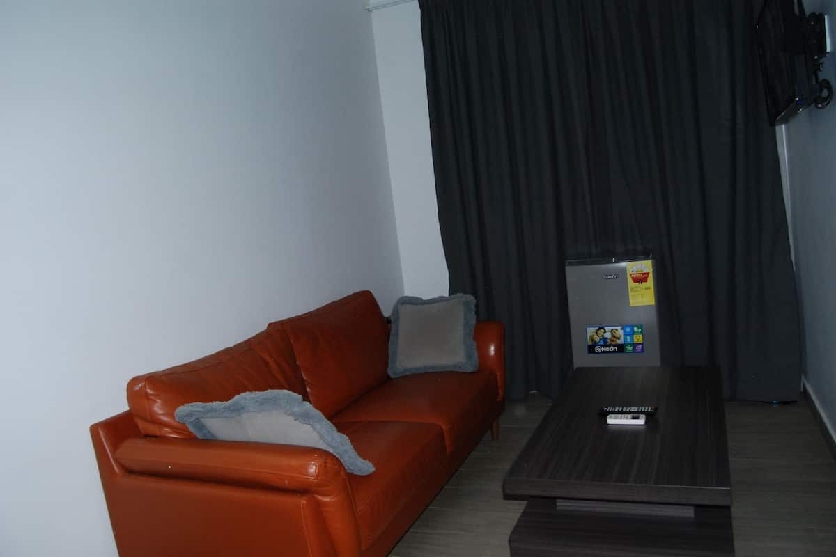 A living room with a brown leather sofa, a small table, and a TV on a stand.