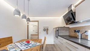 A modern kitchen with a wooden dining table, pendant lights, and built-in appliances. - Apartment 'Holzwieb' with Private Terrace, Shared Garden and Wi-Fi (Unterkirnach)