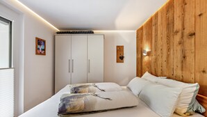 A bedroom with a bed, a wardrobe, and a wooden accent wall. - Apartment 'Holzwieb' with Private Terrace, Shared Garden and Wi-Fi (Unterkirnach)