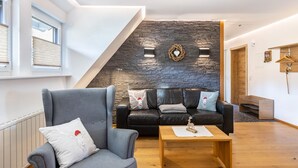 Un salon moderne avec un mur d’accent en pierre, des canapés en cuir et une table basse en bois.