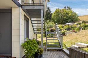 Il s’agit d’une propriété résidentielle dotée d’un escalier menant à un balcon, entourée de verdure et disposant d’un jardin clos.