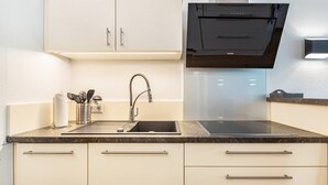 A modern kitchen with a stainless steel sink, a range hood, and white cabinetry.