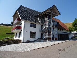 Una casa a due piani con un balcone, una scala e il numero 21 sulla parete.
