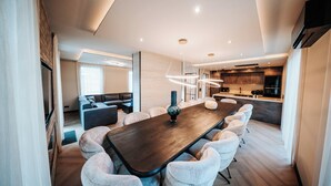 A modern dining area with a long table, cushioned chairs, and pendant lighting. - Beautiful Holiday Home in Waarland (Waarland)