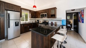 A modern kitchen with dark wood cabinets, stainless steel appliances, a central island, and a red pendant light. - Sunlit Pool Hideaway ● 2 En-Suite Kings (Sosúa)
