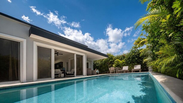 A modern poolside area with a clear blue pool, a covered seating area, and lush greenery. - Sunlit Pool Hideaway ● 2 En-Suite Kings (Sosúa)
