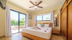 A bedroom with a bed, a ceiling fan, a nightstand, a wardrobe, and a sliding glass door to a balcony. - Modern 3BR Villa · Private Pool · Casa Linda Sosúa (Sosúa)