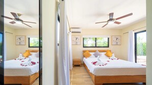 A mirrored view of a hotel room with two beds, ceiling fans, artwork on the walls, and a window with a view of greenery. - Modern 3BR Villa · Private Pool · Casa Linda Sosúa (Sosúa)