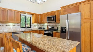 A kitchen with wooden cabinets, granite countertops, stainless steel appliances, and a chandelier. - Modern 3BR Villa · Private Pool · Casa Linda Sosúa (Sosúa)