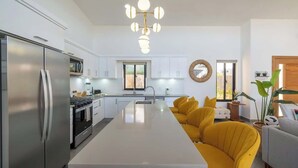 Una cocina moderna con una isla central, electrodomésticos de acero inoxidable y un sofá amarillo.