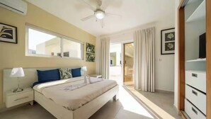 A bedroom with a bed, a nightstand, a ceiling fan, a window, and a door leading to a balcony. - Luxurious 4-bedroom villa in Casa Linda. (Sosúa)