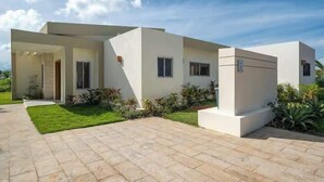 A modern two-story house with a paved driveway, a covered patio, and a well-maintained lawn. - Luxurious 4-bedroom villa in Casa Linda. (Sosúa)
