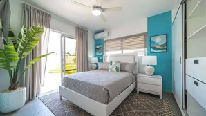 A bedroom with a bed, bedside tables, a ceiling fan, a window with curtains, a potted plant, and a wall-mounted air conditioner. - Private Pool • Luxury • Casa Linda (Sosúa)