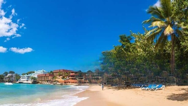 A beach with clear turquoise water, a sandy shore, and a row of buildings with balconies overlooking the sea. - Private Pool • Luxury • Casa Linda (Sosúa)
