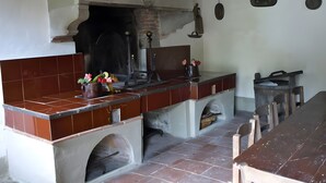 Een keuken met een betegelde spatwand, een bakoven en een lange houten tafel.
