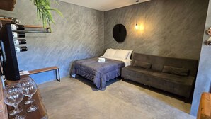A cozy room with a bed, a sofa, a small table, and a TV. - Villa da Serra Studio Ibitipoca (Lima Duarte)