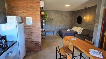 Um espaço compacto com cozinha compacta, área de refeições e sala de estar com sofá e mesa.