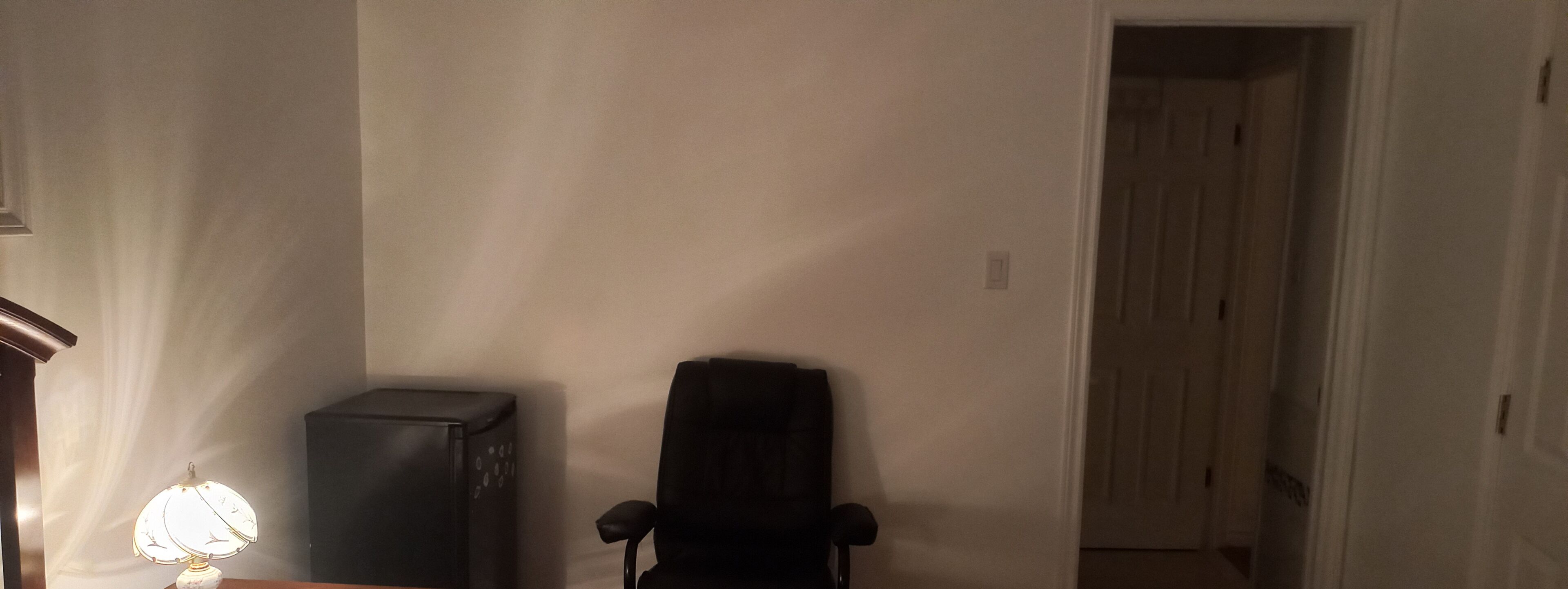 A room with a desk, a lamp, and a chair.