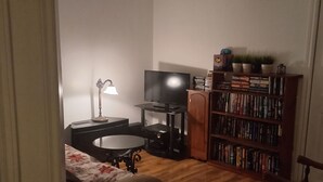A compact living room with a television, a bookshelf, a small table, and a lamp. - Walk out to Salmon Creek (Bowmanville)