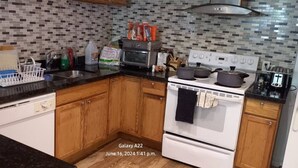 A kitchen with wooden cabinets, a white stove, and a tiled backsplash. - Walk out to Salmon Creek (Bowmanville)