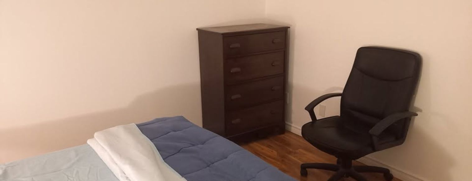 Una habitación con una cama, un aparador y una silla de escritorio.