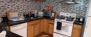 A kitchen with wooden cabinets, a white stove, and a tiled backsplash. - Walk out to Salmon Creek (Bowmanville)