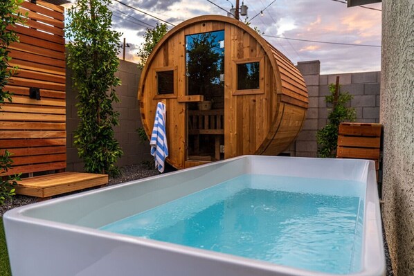 Une structure de sauna en bois avec une piscine rectangulaire devant.