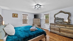 Un dormitorio con cama, cómoda, televisor y espejo.