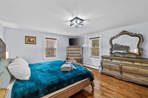 A bedroom with a bed, dresser, TV, and a mirror. - Cozy Farmhouse: Fireplace + Backyard + BBQ + Games (Tannersville)