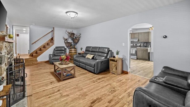 Una sala de estar moderna con un sofá de cuero gris, una mesa de centro de madera y una escalera que lleva a una cocina.
