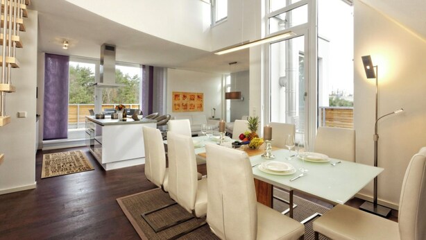 Un espace repas moderne avec une longue table, des chaises blanches et une composition florale à base de fruits.