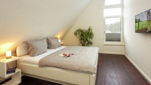 Une chambre à coucher avec un lit, une table de chevet, une lampe et une fenêtre.
