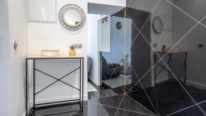 Een moderne badkamer met een zwarte marmeren vloer, een witte wastafel met spiegel, en een kleine plant op het aanrecht.