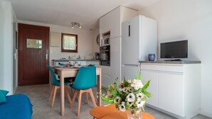A compact living space with a dining area, kitchenette, and a television.