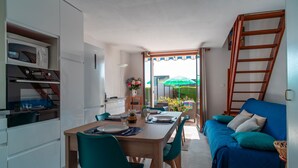 A compact living space with a dining area, a sofa, a staircase, and a view of the outdoors.