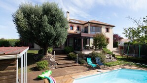 Une maison avec une piscine, une terrasse en bois et un patio couvert.