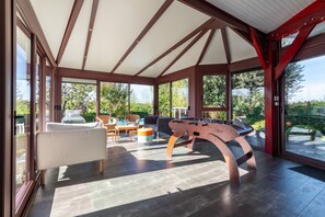 Una habitación amplia con una mesa de futbolín, un sofá y una zona de comedor con sillas y una mesa.