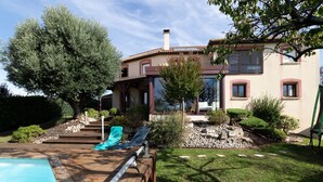 Un espace aménagé au bord de la piscine, avec une terrasse en bois, une chaise longue et une petite piscine.