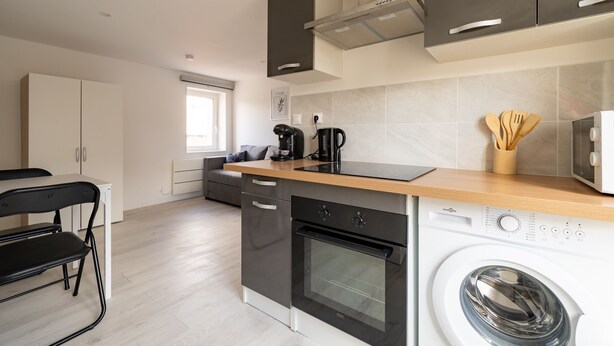 A modern kitchen with a dishwasher, oven, and microwave. - Le Nid du Beffroi - Studio centre Doullens (Doullens)