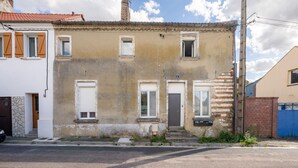 A two-story building with a weathered facade, a small front porch, and a visible chimney. - Le Nid du Beffroi - Studio centre Doullens (Doullens)
