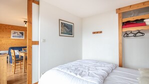 Ein Schlafzimmer mit einem Bett, Holzmöbeln, einem Gemälde und einem Holzregal mit Kleidung.